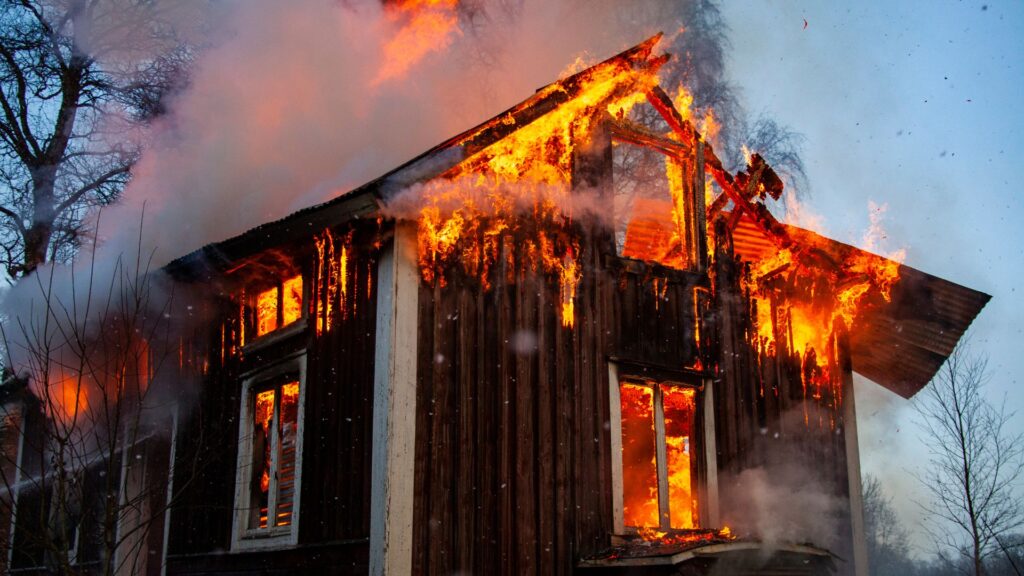地震の二次災害により火元が拡大し、炎に包まれて激しく燃えている木造の建物。